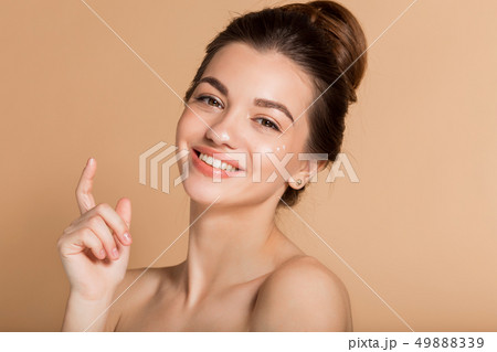 Happy smiling girl with perfect skin with moisturizing face cream on a cheek. Skin care and health Happy smiling girl with perfect skin with moisturizing face cream on a cheek. Skin care and health 49888339
