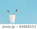 Two wooden toothbrushes in cup on blue background. 49888553