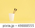 Two wooden toothbrushes in cup on yellow background. 49888555