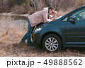 Young man is watching road map on hood of car near the river. 49888562