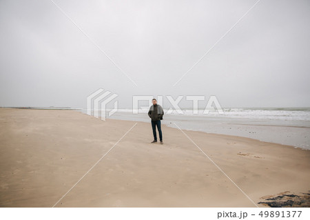 Male tourist walkin along the North Sea. Man with backpack stand on the coast in rainy weather 49891377