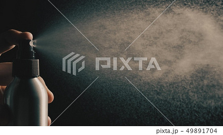 Sprinkling water or perfume against dark background Sprinkling water or perfume against dark background 49891704