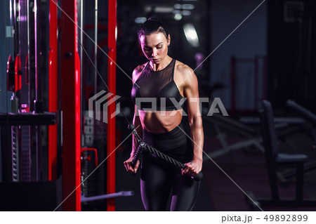 Athletic sexy woman doing exercise using machine in gym - side view Athletic sexy woman doing exercise using machine in gym - side view 49892899