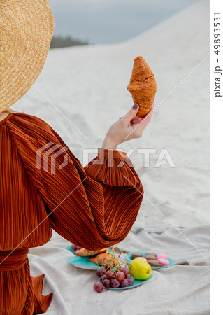 young woman with croissant have lunch on a litter on a beach young woman with croissant have lunch on a litter on a beach 49893531