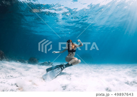 Freediver young woman with fins swim over sand Freediver young woman with fins swim over sand 49897643