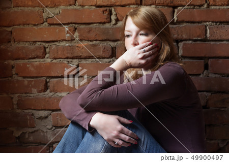 Side view of a depressed young redhead woman Side view of a depressed young redhead woman 49900497