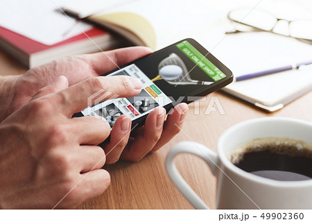 スマートフォンでゴルフのネットショッピングをする男性の手のアップ。 スマートフォンでゴルフのネットショッピングをする男性の手のアップ。 49902360