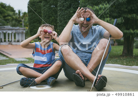 Happy father and little son playing mini golf. Happy father and little son playing mini golf. 49910861