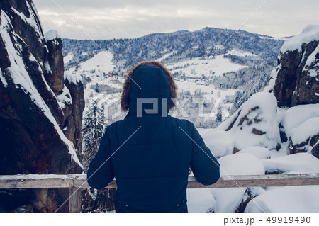 The figure of a traveller ascending to a mountain summit against the background of a snow-covered The figure of a traveller ascending to a mountain summit against the background of a snow-covered 49919490