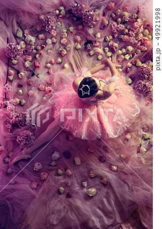Young woman in pink ballet tutu surrounded by flowers 49921998