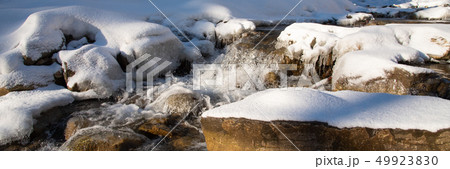 Water flowing in rapids over stone, in the winter mountains 49923830