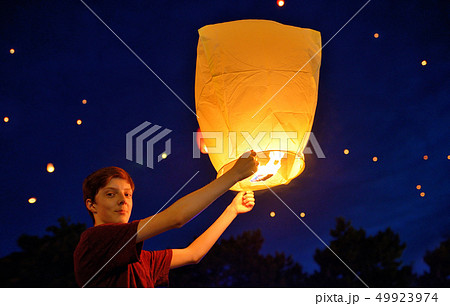 Teen boy in night with paper lantern Teen boy in night with paper lantern 49923974