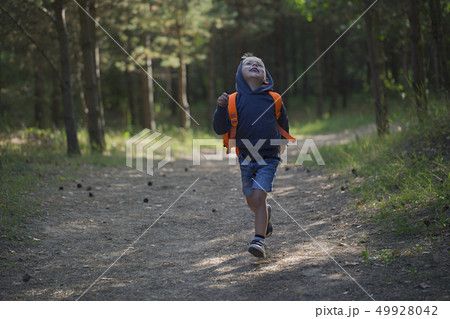 A happy little boy runs along a forest path A happy little boy runs along a forest path 49928042
