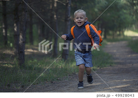 A happy little boy runs along a forest path A happy little boy runs along a forest path 49928043