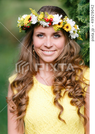 Portrait young girl in yellow dress with Flower wreath for head. Walking in park, Warm summer day. 49929042