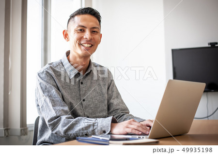 パソコンの前に座る笑顔の男性 49935198
