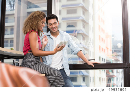 Couple using digital tablet together in coworking 49935695