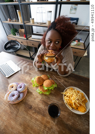 Emotional curly haired female eating junk food Emotional curly haired female eating junk food 49941110