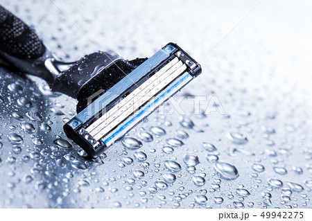 Razor close-up with water drops on a gray background. Razor close-up with water drops on a gray background. 49942275