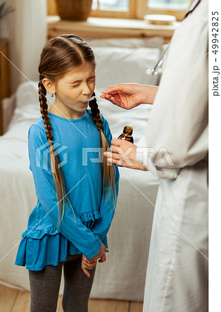 Small girl being made to drink syrup by a pediatrician Small girl being made to drink syrup by a pediatrician 49942825