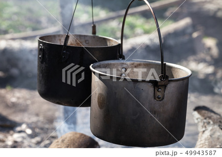 Cooking in two sooty old cauldrons on campfire at Cooking in two sooty old cauldrons on campfire at 49943587