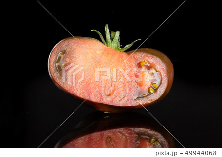 Fresh dark tomato primora isolated on black glass Fresh dark tomato primora isolated on black glass 49944068