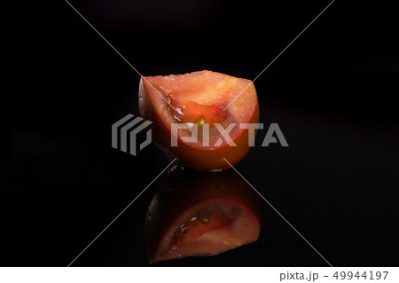 Fresh dark tomato primora isolated on black glass Fresh dark tomato primora isolated on black glass 49944197
