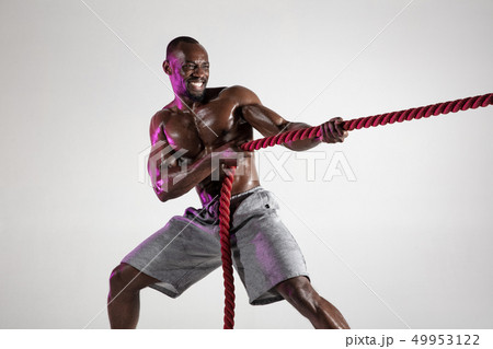Young african-american bodybuilder training over grey background Young african-american bodybuilder training over grey background 49953122
