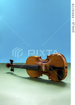 Musical stringed instrument violin on a colored Musical stringed instrument violin on a colored 49956728