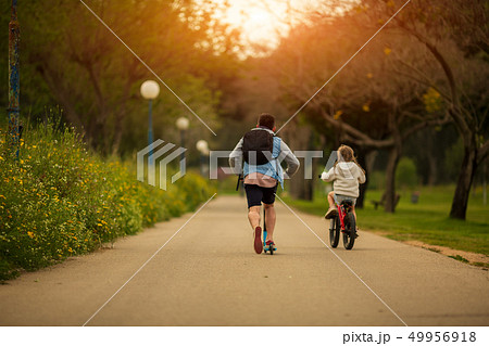 dad with daughter on bicycle and scooter dad with daughter on bicycle and scooter 49956918