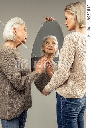 Nice good looking aged woman touching the mirror 49973619