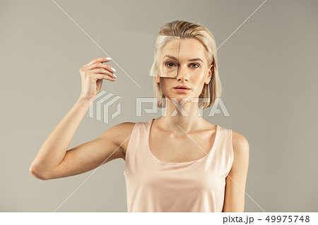 Nice young woman putting a mirror to the eye 49975748