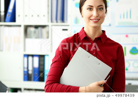 Beautiful smiling girl in red blouse at workplace look in camera Beautiful smiling girl in red blouse at workplace look in camera 49978439