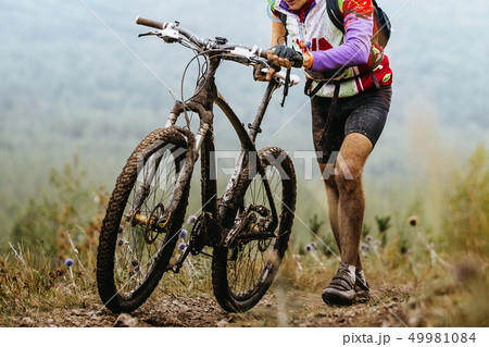dirty cyclist climbing mountain trail 49981084