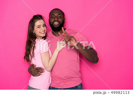 Waist up of smiling interracial couple looking at camera in studio Waist up of smiling interracial couple looking at camera in studio 49982113