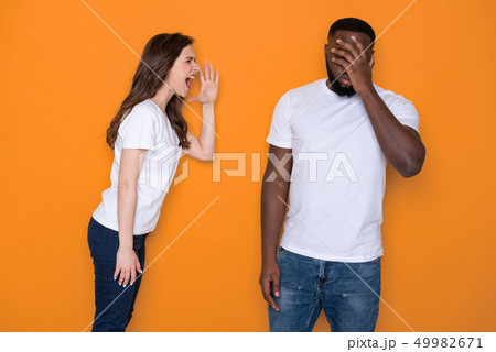 Waist up of nervous interracial couple in white T-shirts posing for camera Waist up of nervous interracial couple in white T-shirts posing for camera 49982671