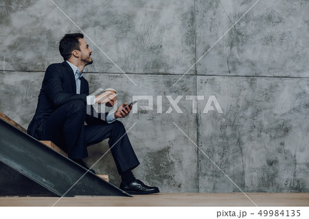 Merry businessman with smartphone is enjoying coffee 49984135