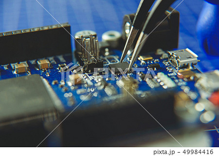 Microcircuit with tweezers on the background of electronic components 49984416