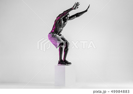 Young african-american bodybuilder training over grey background Young african-american bodybuilder training over grey background 49984883
