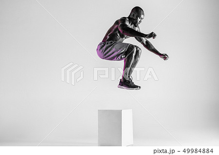 Young african-american bodybuilder training over grey background 49984884
