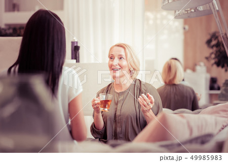 Positive delighted blonde woman drinking tea in salon Positive delighted blonde woman drinking tea in salon 49985983