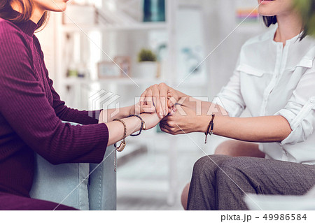 Close-up photo of a psychologist holding hand of female patient Close-up photo of a psychologist holding hand of female patient 49986584