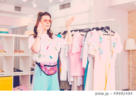 Young woman having a phone conversation in a boutique 49992494
