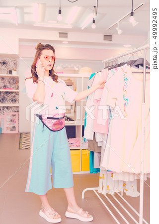 Young woman choosing the dress and talking to her friend Young woman choosing the dress and talking to her friend 49992495