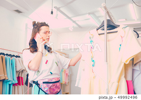 Woman having a phone conversation while buying closes 49992496
