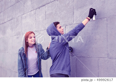 Dangerous young guy coloring city walls with spray paints 49992617