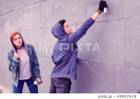 Extremal dark-haired guy using bottle of spray paints 49992618