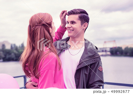 Lovely long-haired girl correcting hairstyle of her smiling boyfriend 49992677
