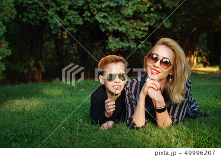 Mother and son are lying on lawn in park Mother and son are lying on lawn in park 49996207