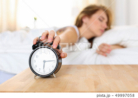 Sleepy young woman trying kill alarm clock 49997058